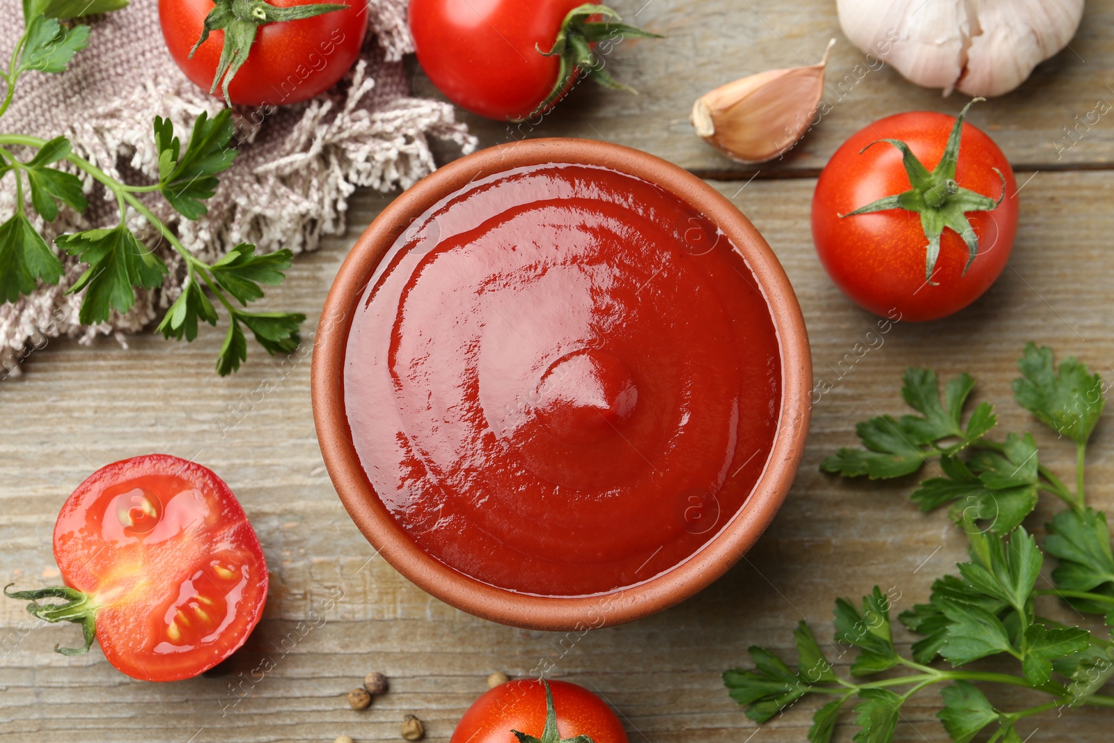 Photo of Tasty ketchup, fresh tomatoes, parsley and spices on wooden table, flat lay