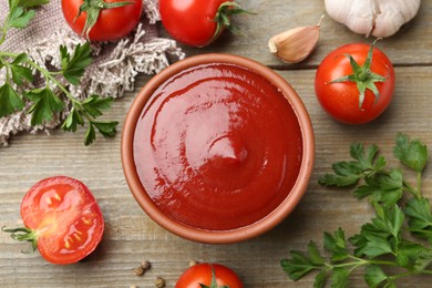 Tasty ketchup, fresh tomatoes, parsley and spices on wooden table, flat lay