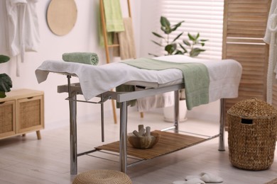 Comfortable massage table with clean towels in spa center