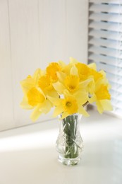 Photo of Beautiful yellow daffodils in vase on windowsill. Space for text