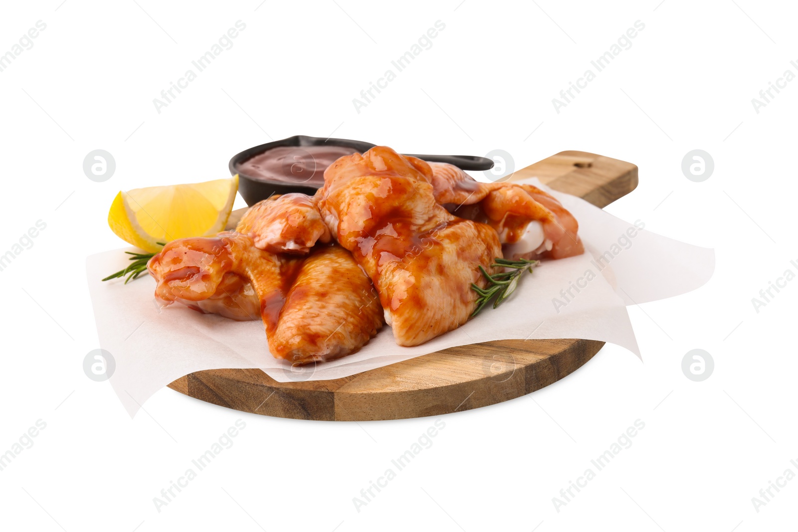 Photo of Board with marinade, raw chicken wings, rosemary and lemon isolated on white