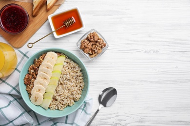 Tasty breakfast with oatmeal porridge on white wooden table, flat lay. Space for text
