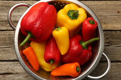 Photo of Metal colander with fresh peppers on wooden table, top view