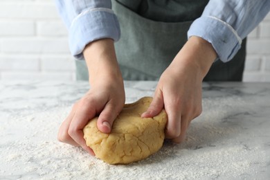 Photo of Making shortcrust pastry. Woman kneading raw dough at white marble table, closeup