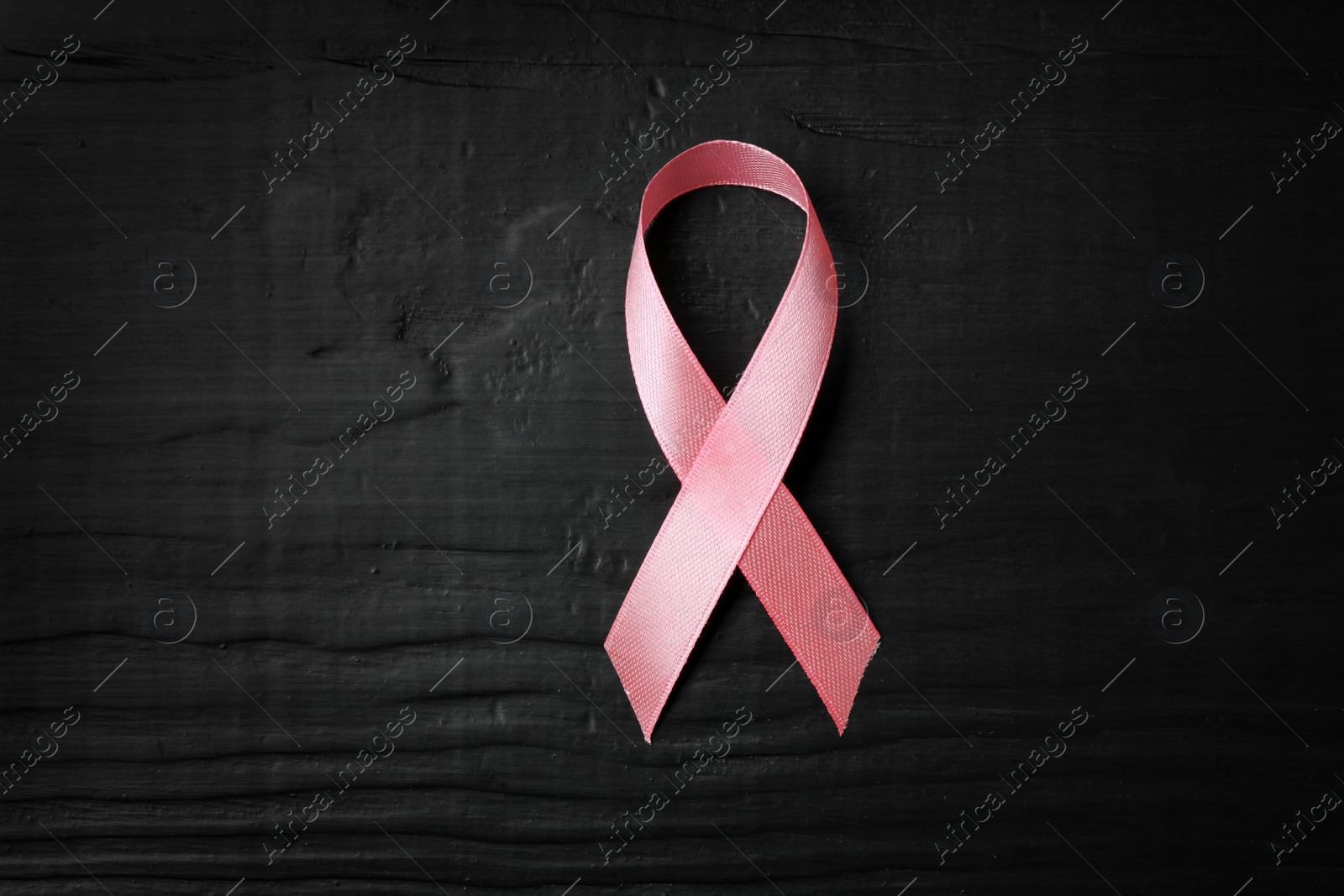 Photo of Pink ribbon on wooden background, top view with space for text. Breast cancer concept