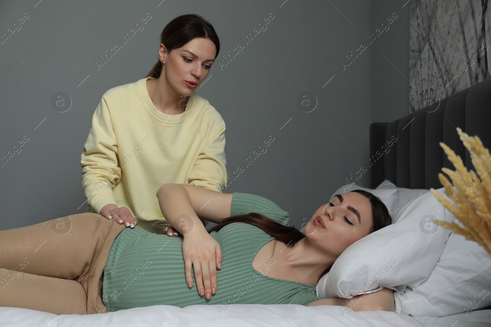 Photo of Doula taking care of pregnant woman in bedroom. Preparation for child birth