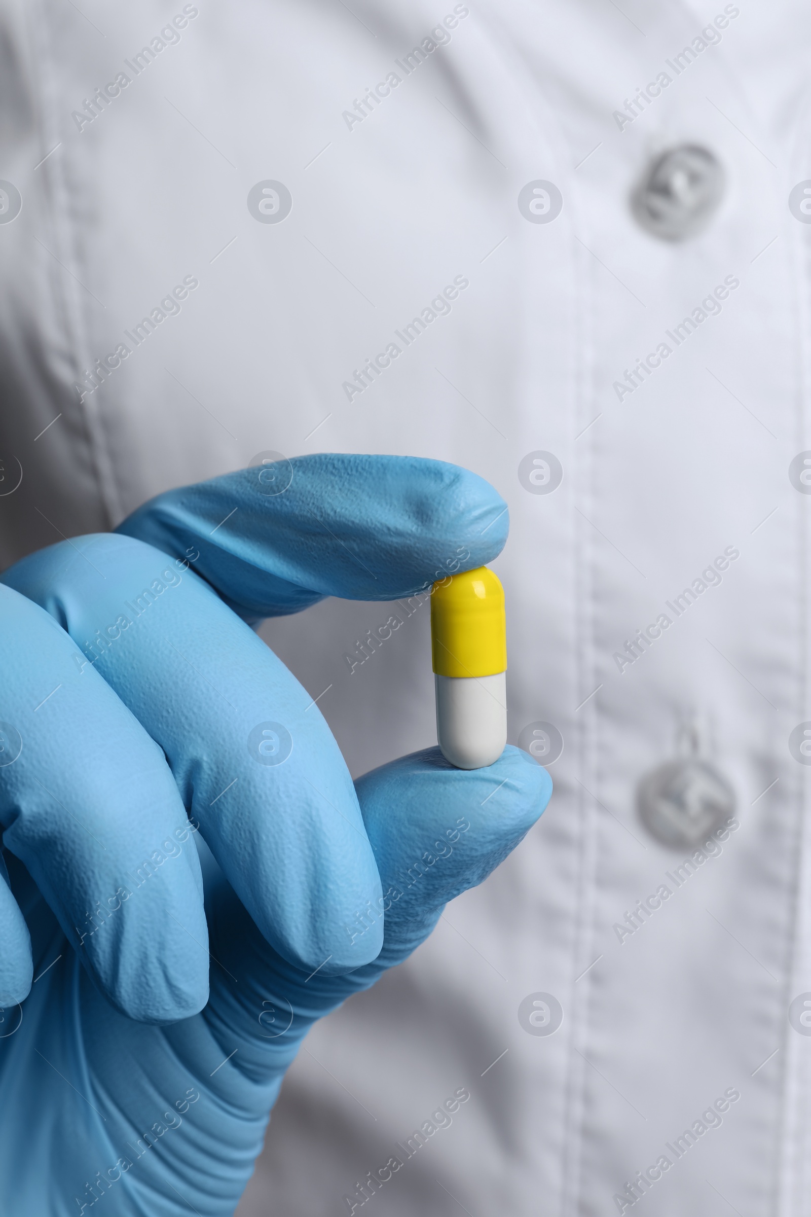 Photo of Doctor in medical glove holding pill, closeup view