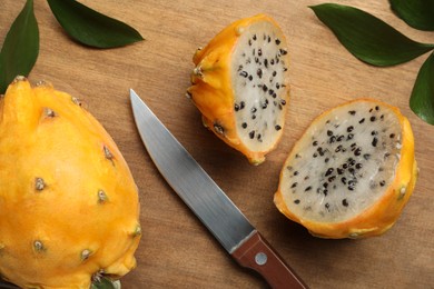 Delicious cut and whole dragon fruits (pitahaya) on wooden table, above view