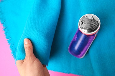 Photo of Woman with light blue scarf and fabric shaver on pink background, top view