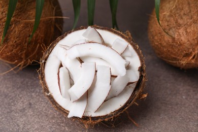 Photo of Coconut pieces in nut shell on brown table