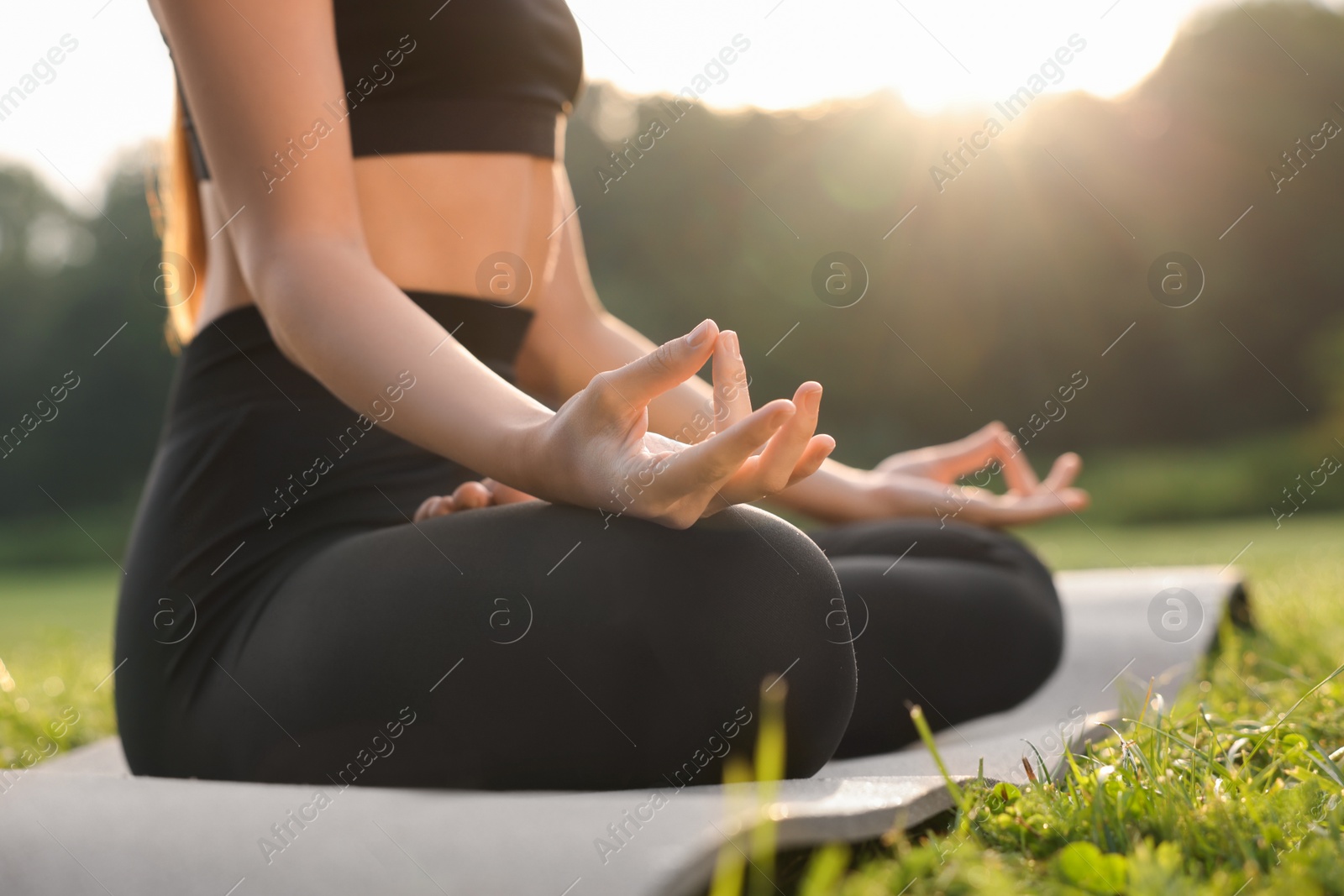 Photo of Woman practicing Padmasana on yoga mat outdoors, closeup. Lotus pose