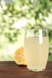 Delicious refreshing drink and lemon on wooden table, closeup