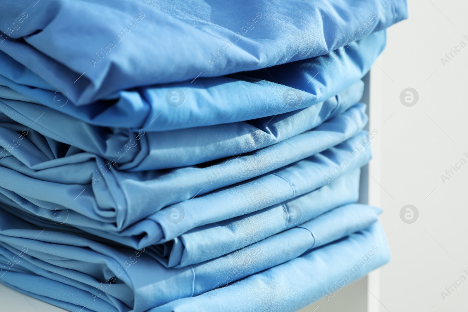 Photo of Light blue medical uniforms on white rack, closeup