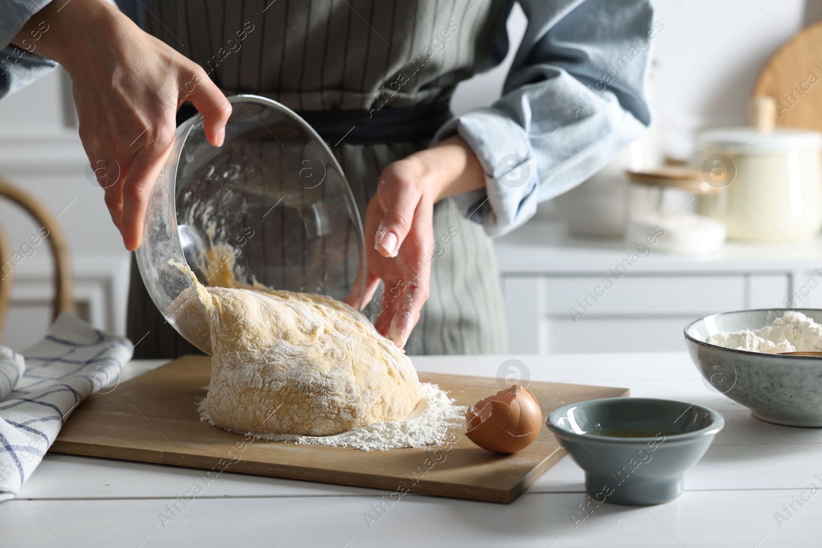 Photo of Woman kneading dough at white wooden table in kitchen, closeup