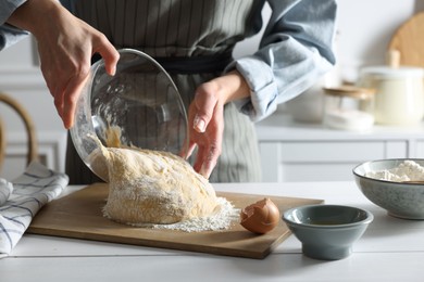 Woman kneading dough at white wooden table in kitchen, closeup