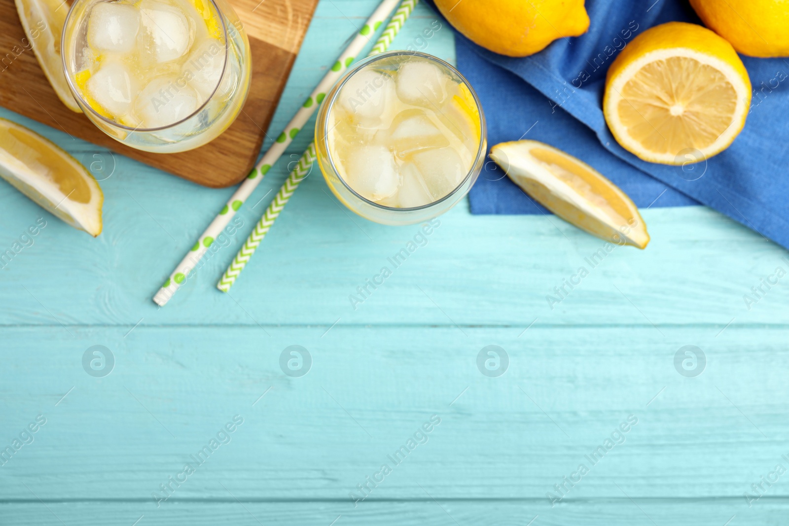 Photo of Soda water with lemon slices and ice cubes on light blue wooden table, flat lay. Space for text