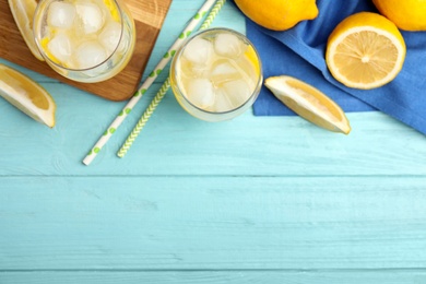 Soda water with lemon slices and ice cubes on light blue wooden table, flat lay. Space for text