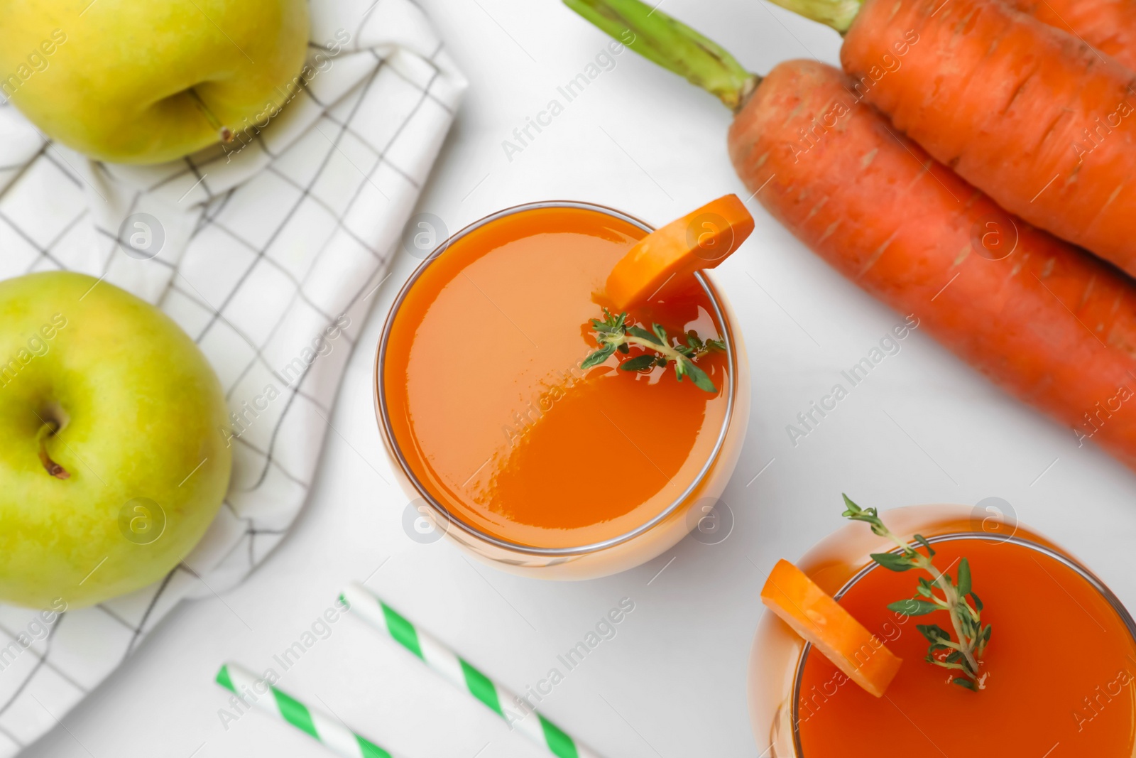 Photo of Glass with healthy carrot juice and ingredients on white table, flat lay