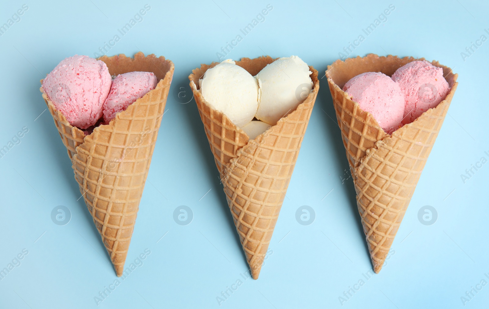 Photo of Delicious ice creams in wafer cones on blue background, flat lay