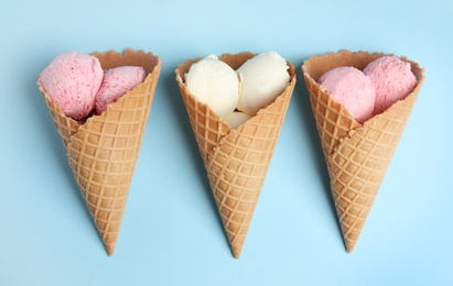 Photo of Delicious ice creams in wafer cones on blue background, flat lay