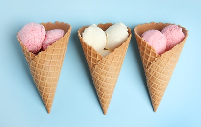 Delicious ice creams in wafer cones on blue background, flat lay