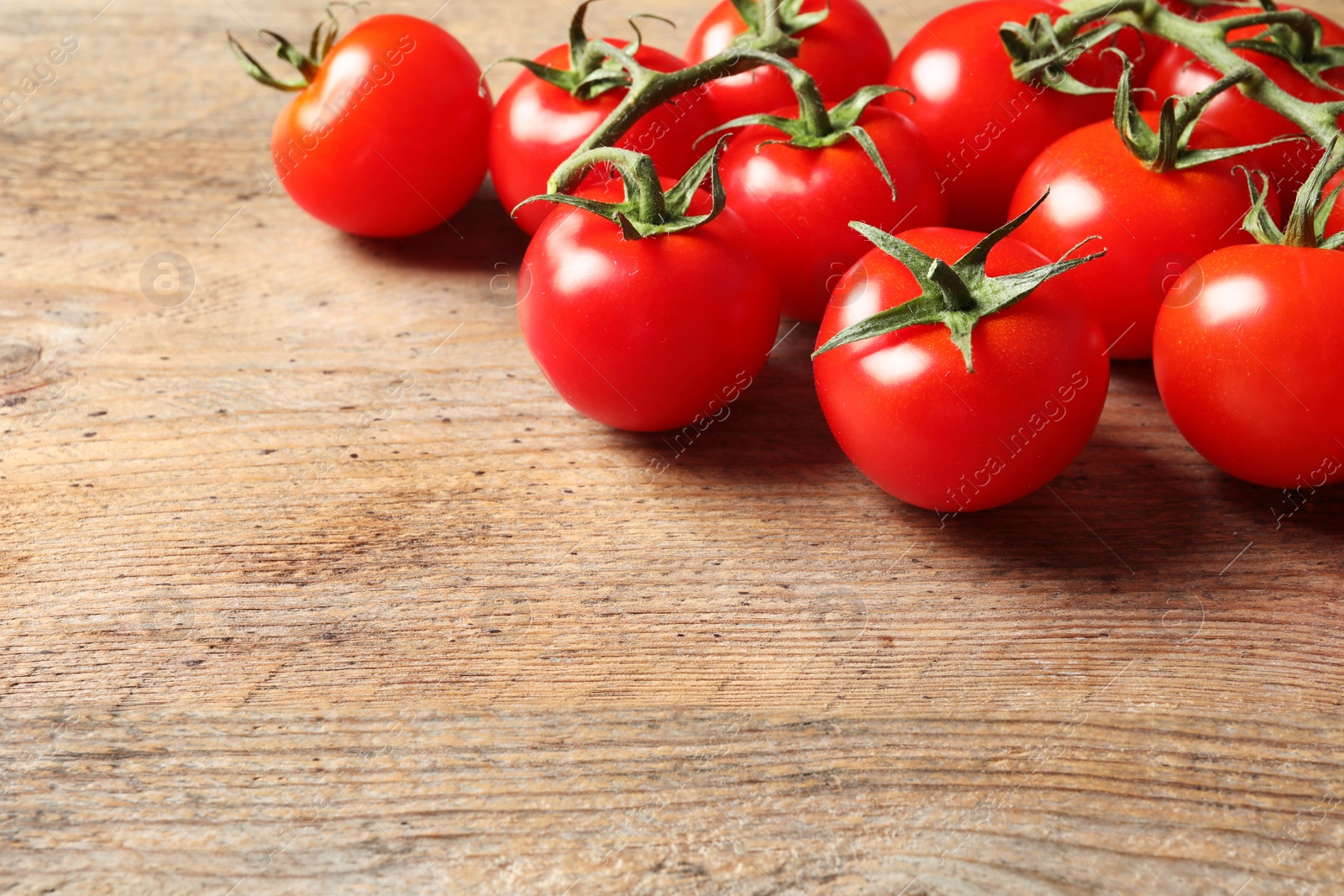 Photo of Fresh cherry tomatoes on wooden background. Space for text