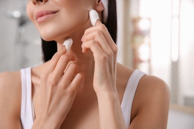 Woman using silkworm cocoons in skin care routine at home, closeup