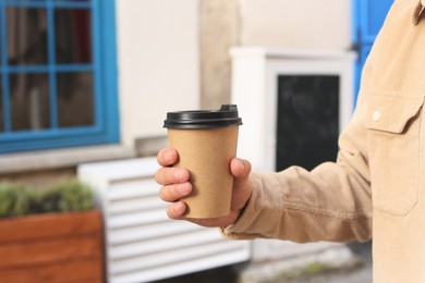 Coffee to go. Man with paper cup of drink outdoors, closeup