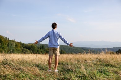 Photo of Feeling freedom. Man with wide open arms on meadow, back view