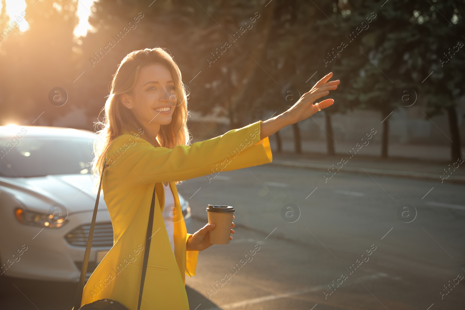 Photo of Young businesswoman catching taxi on city street