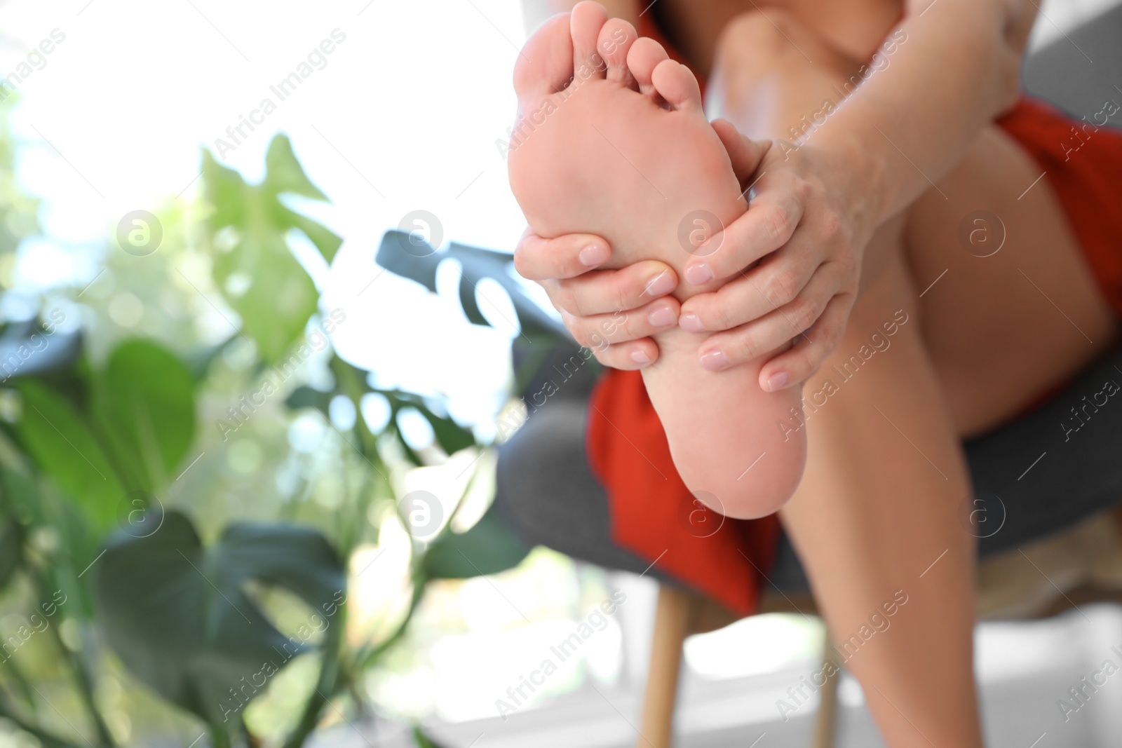 Photo of Woman suffering from foot pain at home, closeup. Space for text