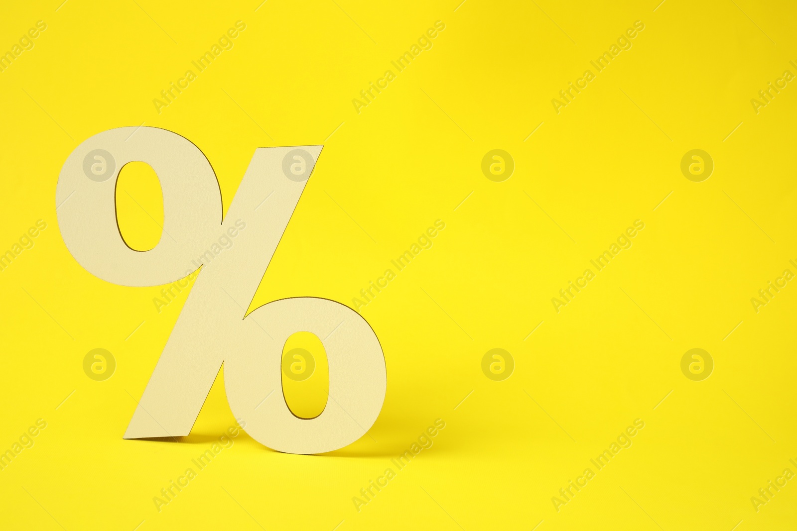 Photo of Wooden percent sign on yellow background. Space for text