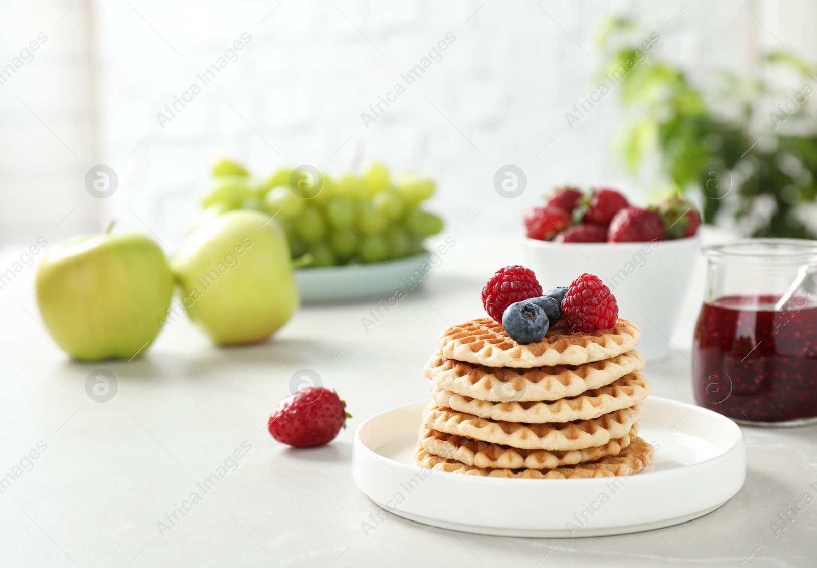 Photo of Delicious breakfast with waffles and berries on light table. Space for text