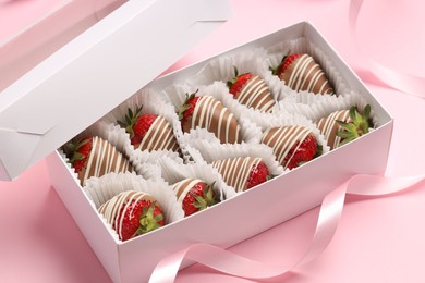 Box with delicious chocolate covered strawberries on pink background