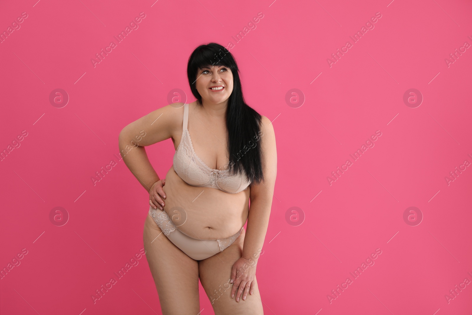 Photo of Beautiful overweight woman in beige underwear on pink background, space for text. Plus-size model