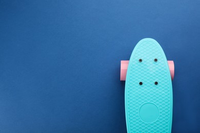 Photo of Turquoise skateboard on blue background, top view. Space for text