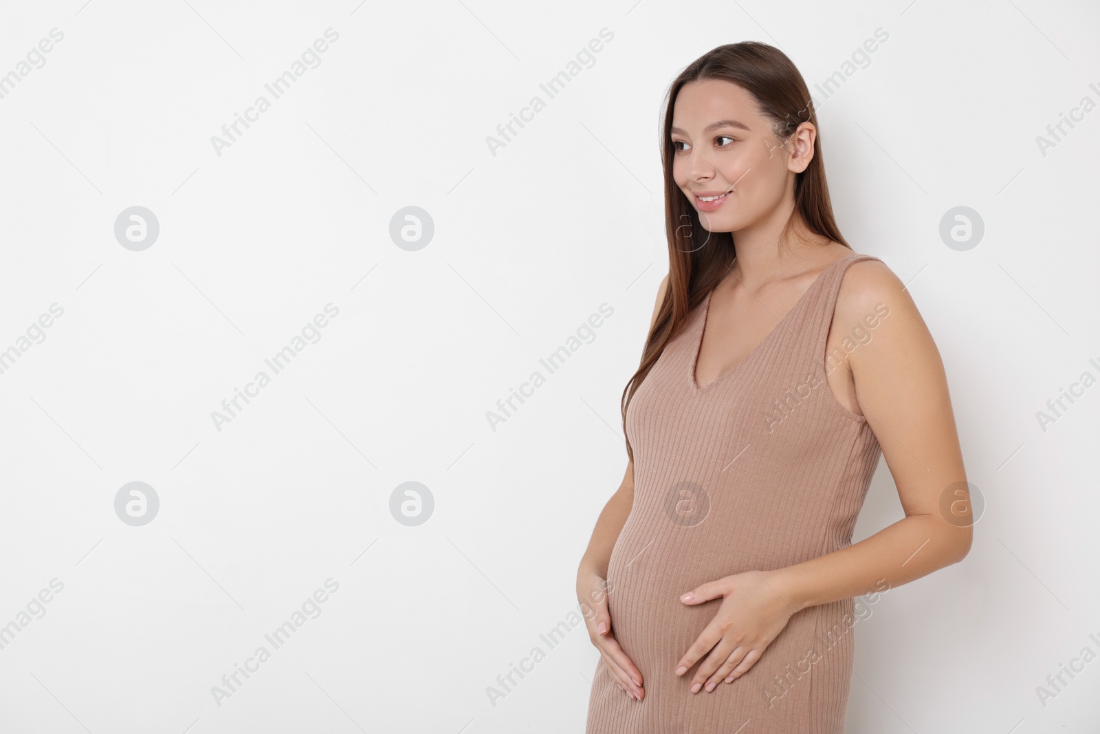 Photo of Beautiful pregnant woman in beige dress on white background, space for text