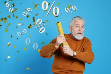 Image of Discount offer. Senior man blowing up party popper on light blue background. Confetti and percent signs in air