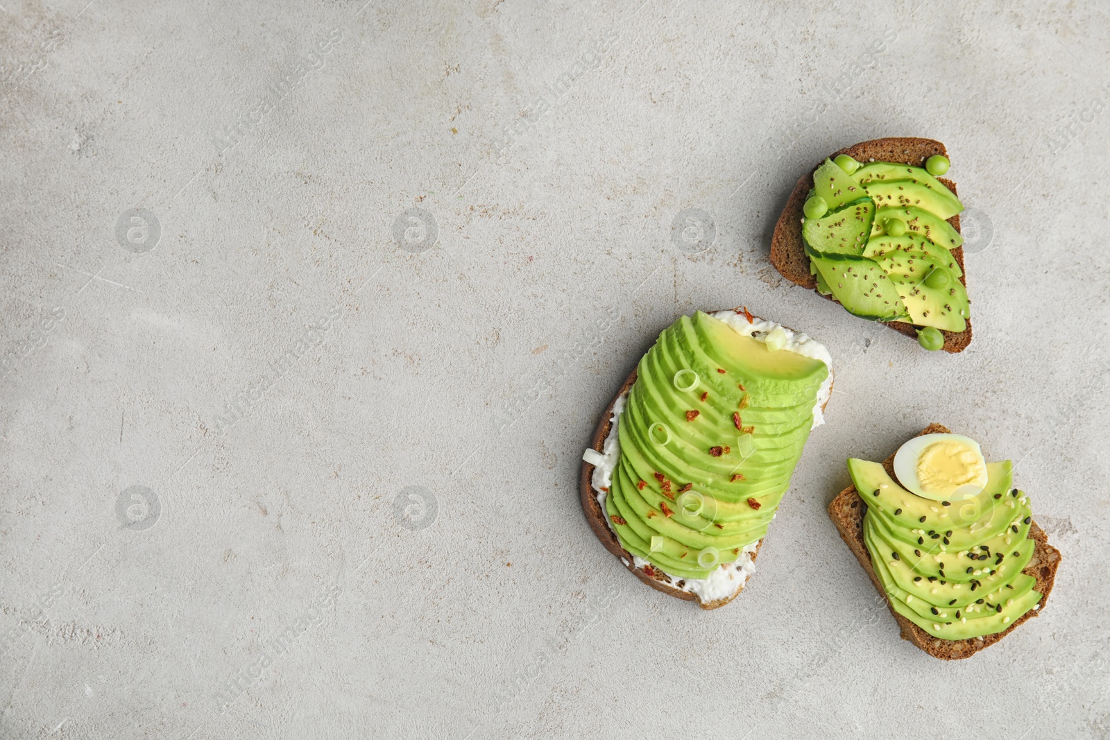 Photo of Tasty crisp rye toasts with avocado on table, flat lay