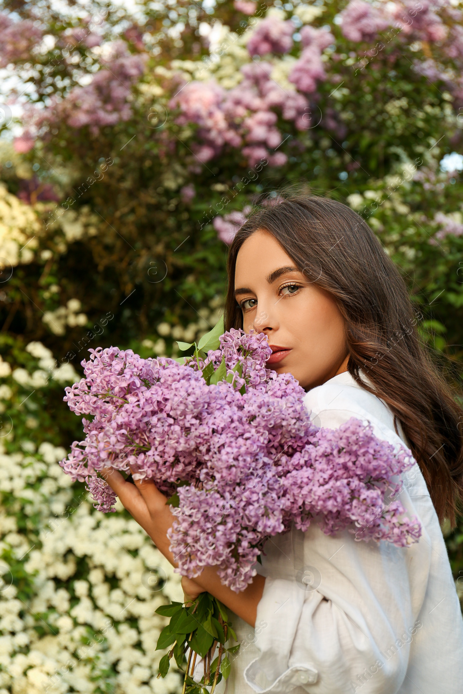 Photo of Attractive young woman with lilac flowers outdoors