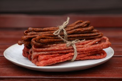 Photo of Bundles of delicious kabanosy on wooden table, closeup