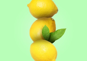 Image of Stack of whole fresh lemons with leaves on light green background