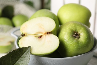 Fresh green apples with water drops in colander, closeup