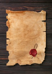Photo of Sheet of old parchment paper with wax stamp on wooden table, top view. Space for text