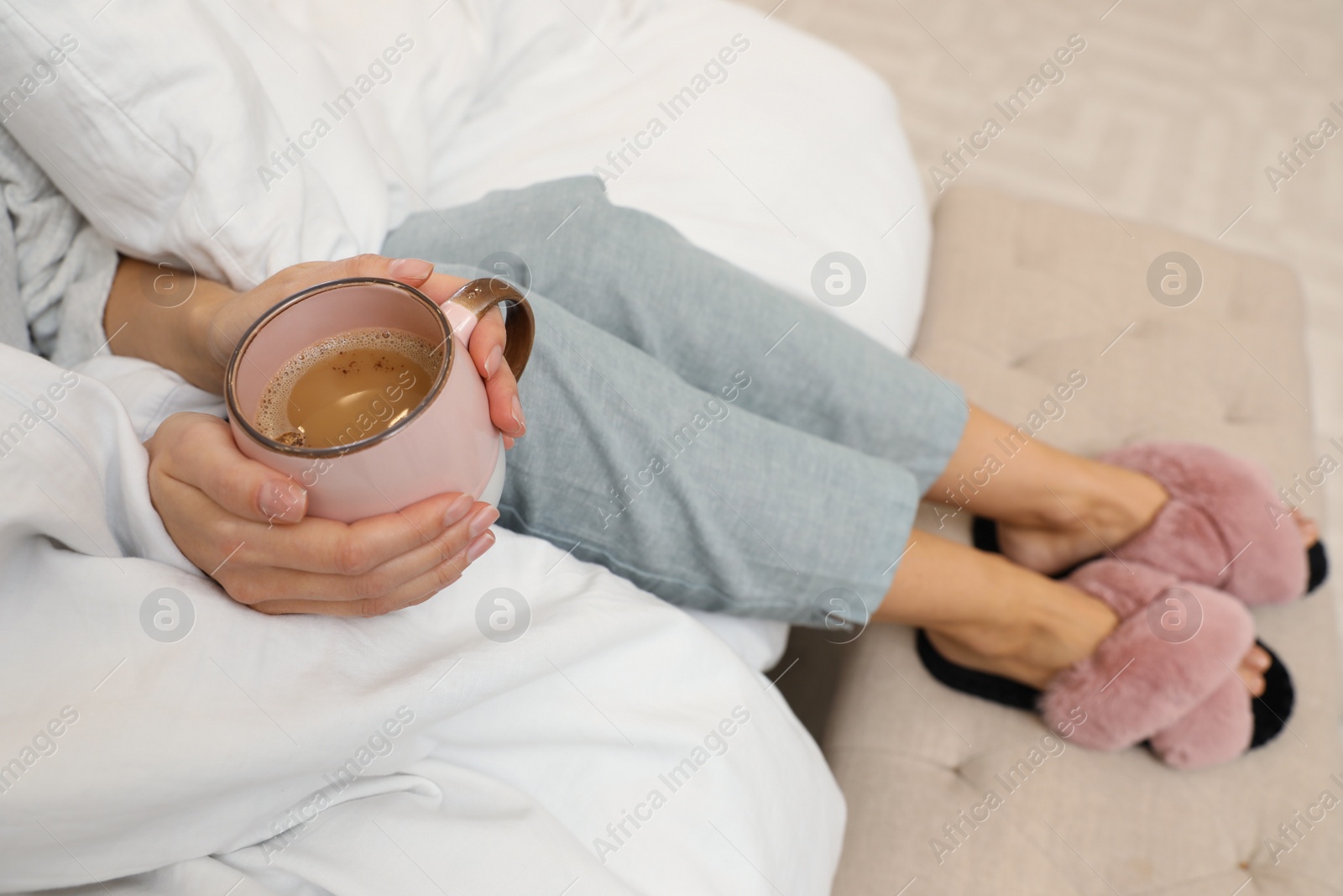 Photo of Woman with cup of coffee and soft blanket on bed, closeup