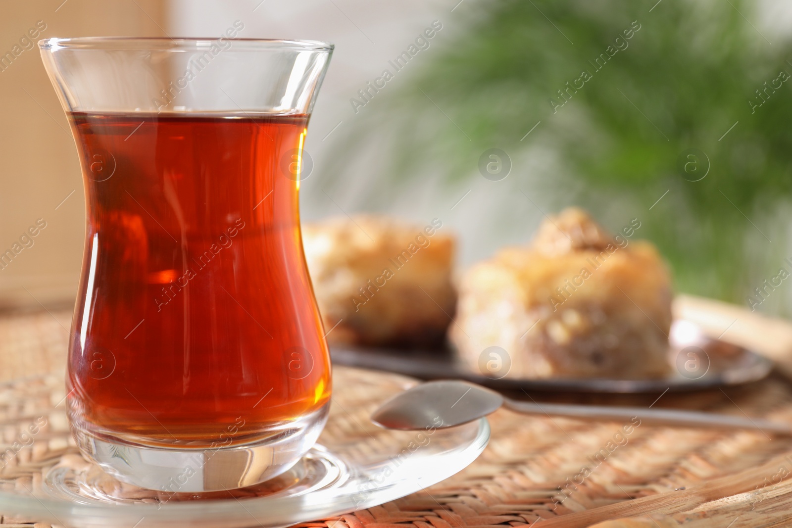 Photo of Traditional Turkish tea in glass on wicker table, closeup. Space for text