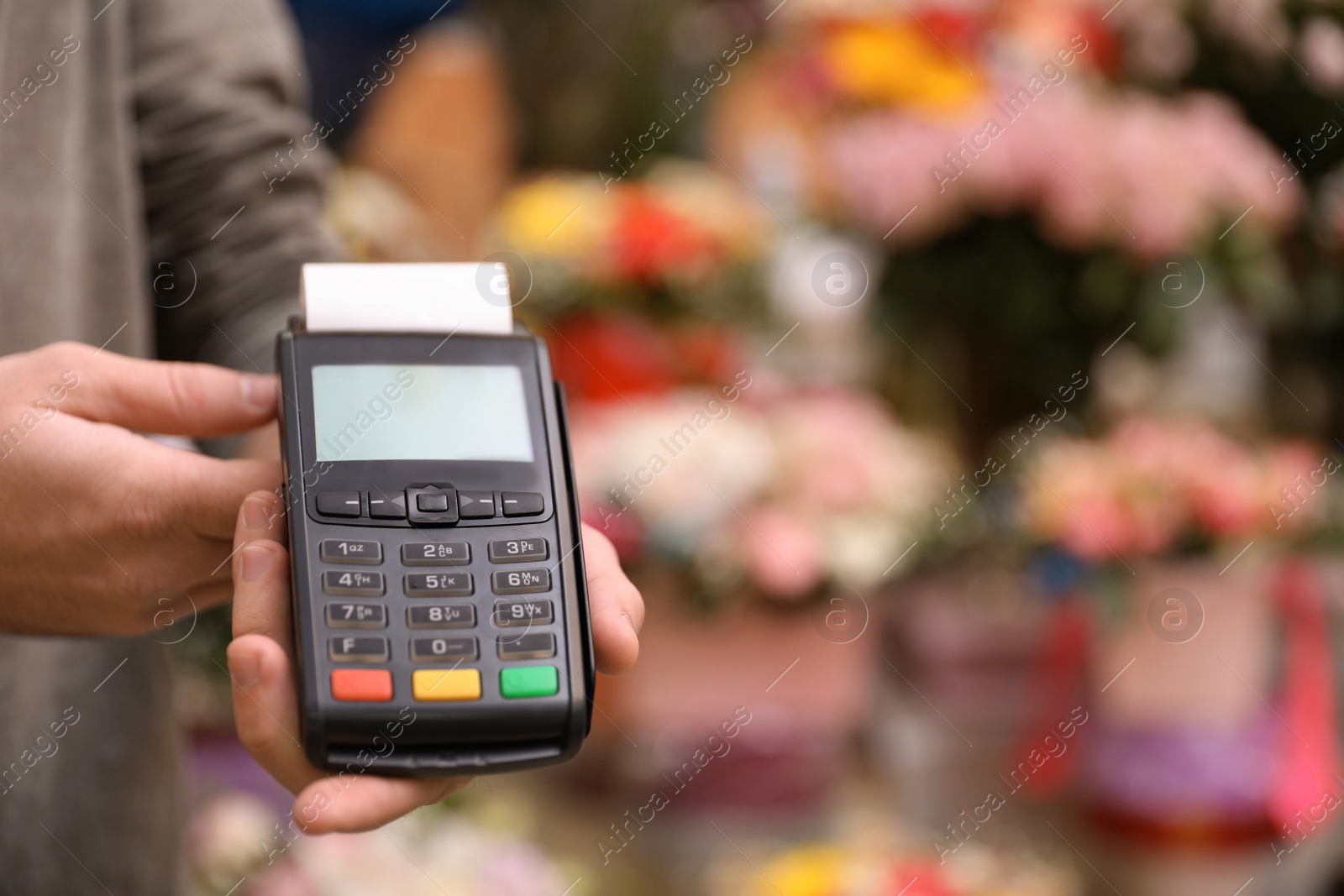 Photo of Man holding payment terminal in floral shop, closeup. Space for text