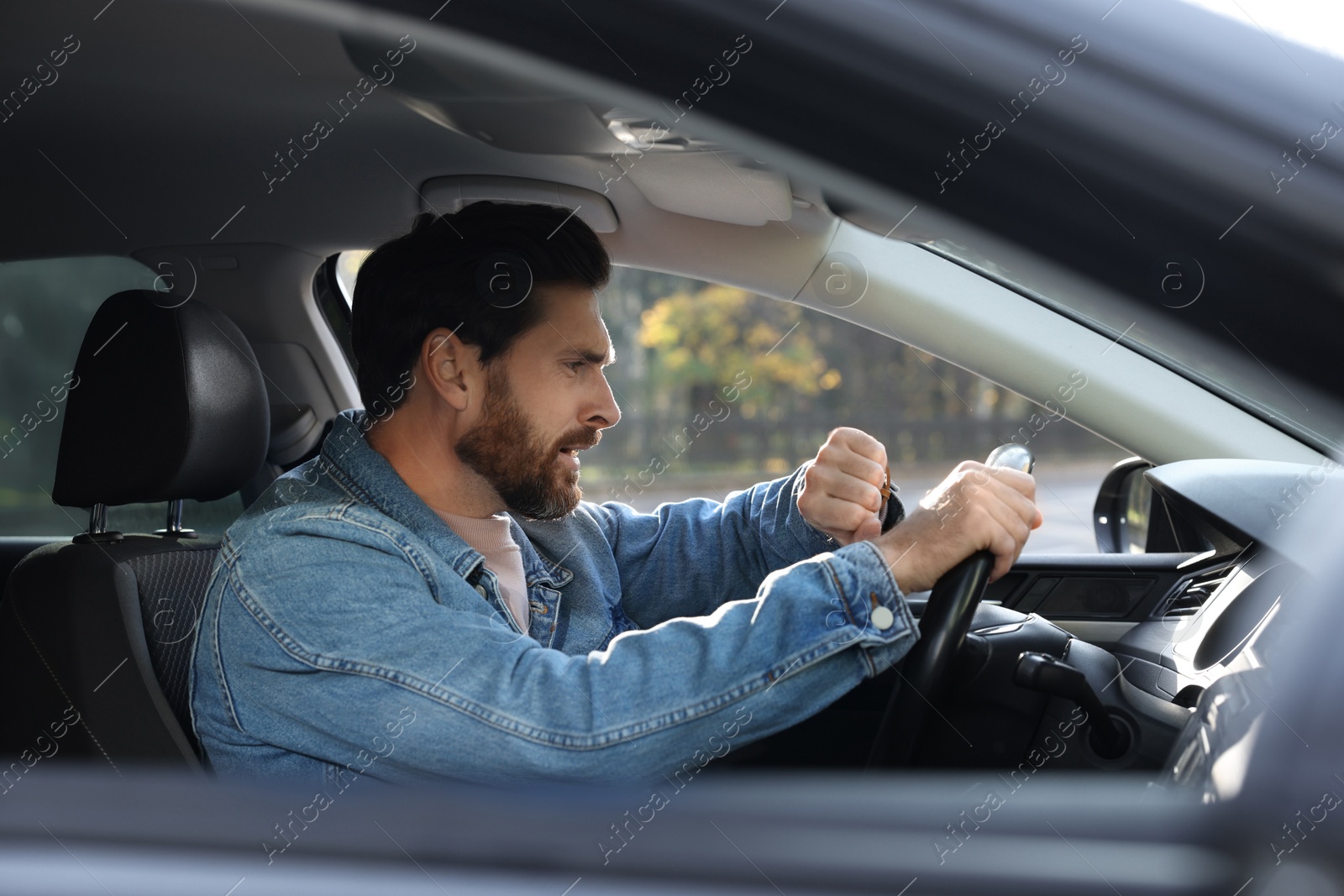 Photo of Emotional man checking time on watch in car. Being late concept