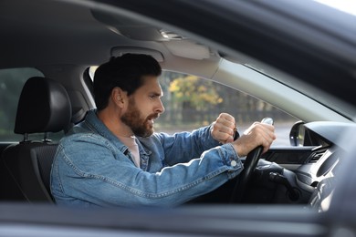 Photo of Emotional man checking time on watch in car. Being late concept