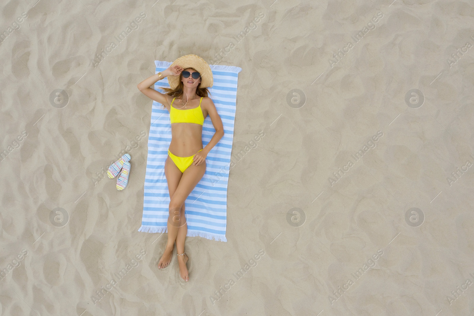 Image of Woman sunbathing on beach towel at sandy coast, aerial view. Space for text